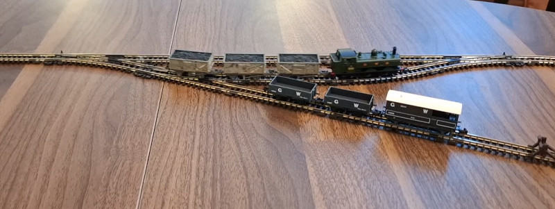 Look, we can shunt things! A model railway on a table, with a loop and a siding. The train is passing through the loop, and there are a few wagons in the siding